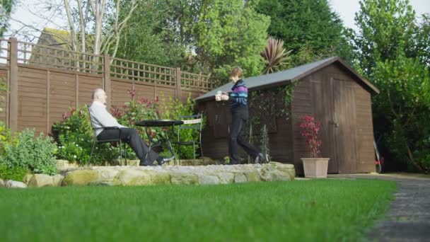 Зрелая пара сидит в саду — стоковое видео
