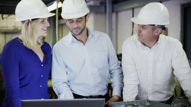 Трое рабочих на складе с ноутбуком обсуждают свою работу . — стоковое видео