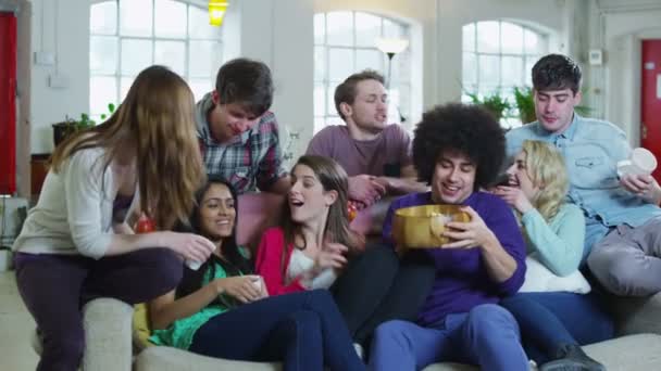 Happy group of friends relaxing on the sofa, eating popcorn and watching TV — Stock Video