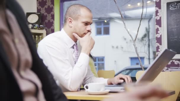 Attraente razza mista giovane maschio professionista che lavora sul suo computer portatile in un caffè — Video Stock