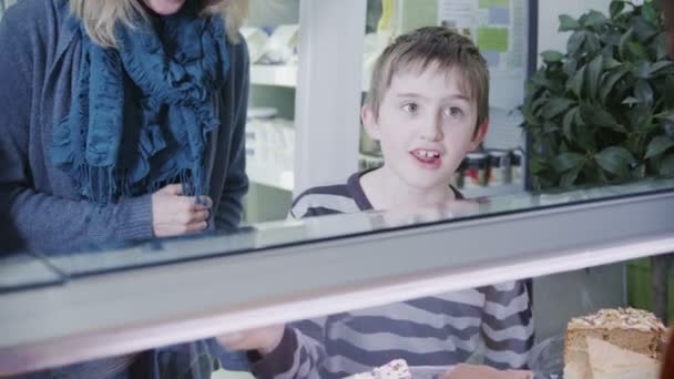 Χαριτωμένο μικρό αγόρι, επιλέγοντας ένα φρέσκα γλυκά στο μετρητή αρτοποιίας — Αρχείο Βίντεο
