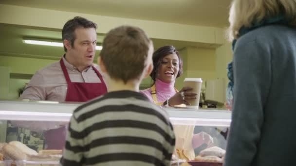 Friendly male and female shopkeepers serving customers with coffee and pastries — Stock Video