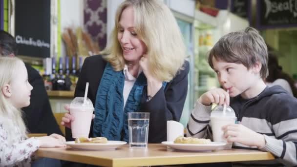 Linda niña en un café disfruta compartiendo su batido — Vídeo de stock