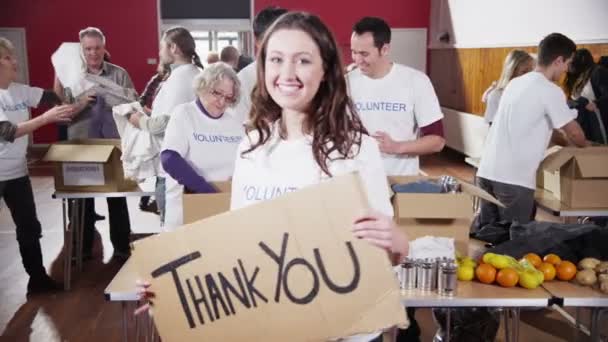 Beautiful female charity worker holds up a Thank you sign to camera — Stock Video