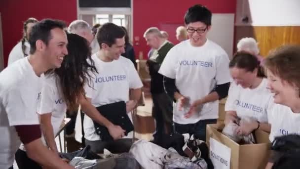 Charity volunteers have fun together as they sort through donated clothing — Stock Video