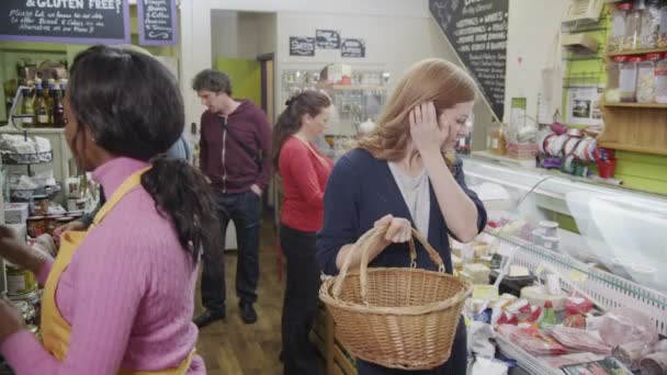 Empregados trabalhando e compradores navegando em uma delicatessen local ou loja de alimentos . — Vídeo de Stock