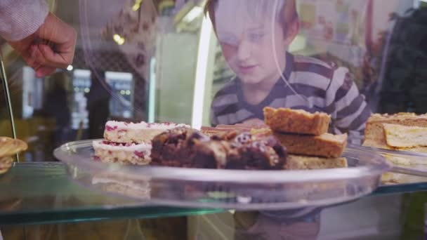 Aranyos kisfiú választva válogatott friss sütemények, egy kávézó és pékség — Stock videók