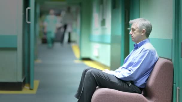 ustaraný muž sedí v nemocnici čekárně