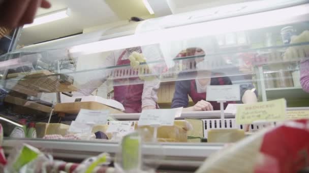 Equipe delicatessen amigável que serve os clientes com um sorriso no balcão de queijo — Vídeo de Stock