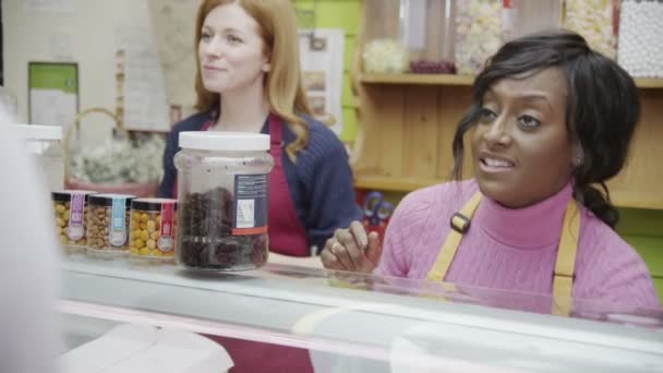 Friendly delicatessen staff serving customers with a smile at the cheese counter — Stock Video