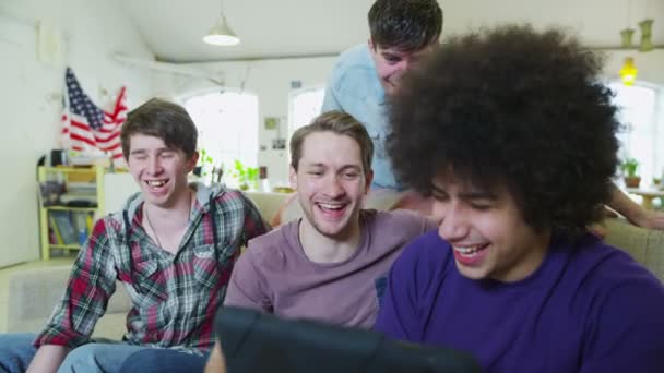 Heureux groupe occasionnel de jeunes amis masculins se détendre avec une tablette informatique — Video