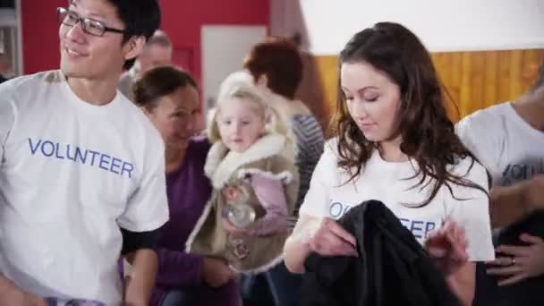 Beautiful charity worker accepts a can of food from cute little blonde girl — Stock Video