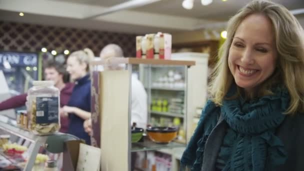 Shopkeeper toma un pago con tarjeta de crédito de una cliente femenina alegre — Vídeos de Stock