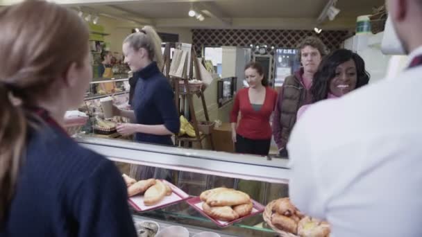 Zufriedene Kunden, die in einem Café Kaffee und frisches Gebäck kaufen — Stockvideo