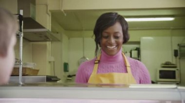 vriendelijke vrouwelijke winkelier bedienen van klanten met vers gebak