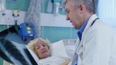 Doktor ile hasta röntgen sonuçlarını tartışıyor