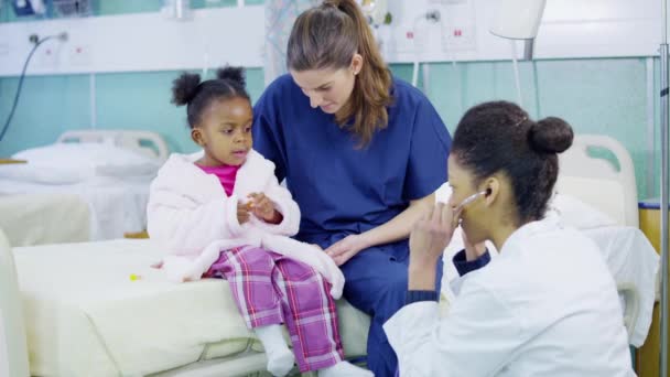 Female doctor uses a stethoscope to examine cute little girl in hospital. — Stock Video