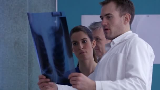 Медицинская команда проверяет рентген пациента — стоковое видео
