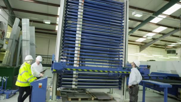 A team of warehouse workers chat together as they operate some heavy machinery — Stock Video