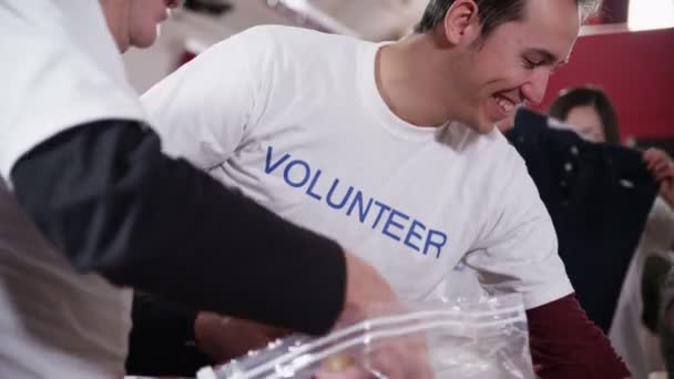 Des bénévoles de tous âges sourient alors qu'ils trient les dons 