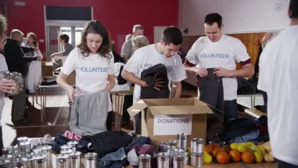 Caridade voluntários triagem através de bens doados — Vídeo de Stock