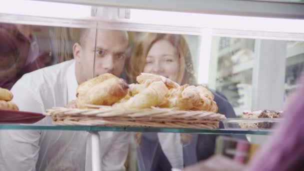 Feliz pareja joven atractiva eligiendo pasteles frescos en el mostrador de la panadería — Vídeos de Stock