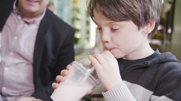 Schattige kleine jongen en meisje milkshakes met hun familie in een café genieten van — Stockvideo