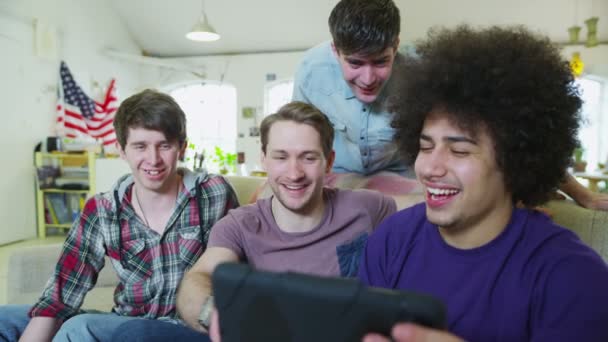 タブレット コンピューターではリラックスした若い男性のお友達の幸せなカジュアルなグループ — ストック動画