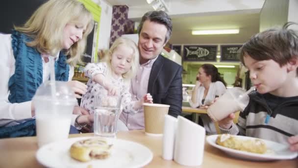 Gelukkig aanhankelijk familie genieten van snacks en drankjes in een café — Stockvideo