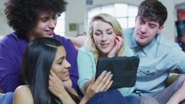 genç arkadaş rahatlatıcı bir tablet bilgisayar ile mutlu rahat grubu