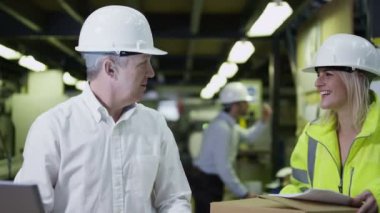 işçilerin bir dizüstü bilgisayar ile bir depoda mal teslimi için hazırlanıyorlar