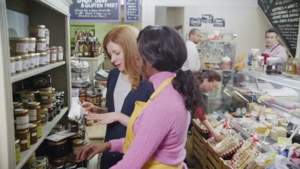 Empleados que trabajan y compradores que navegan en una tienda local de delicatessen o alimentos . — Vídeos de Stock