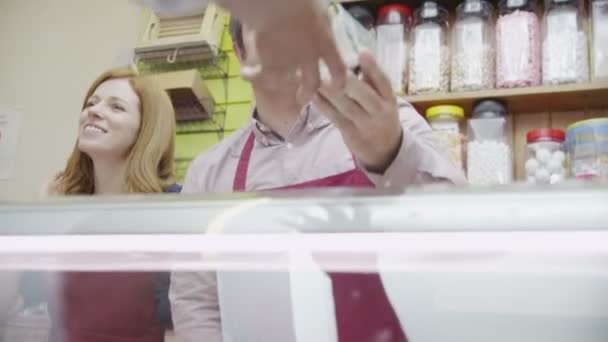 Personal amable de delicatessen que sirve a los clientes con una sonrisa en el mostrador de queso — Vídeo de stock