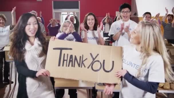 Two Charity workers hold up a Thank you sign as their fellow workers applaud — Stock Video