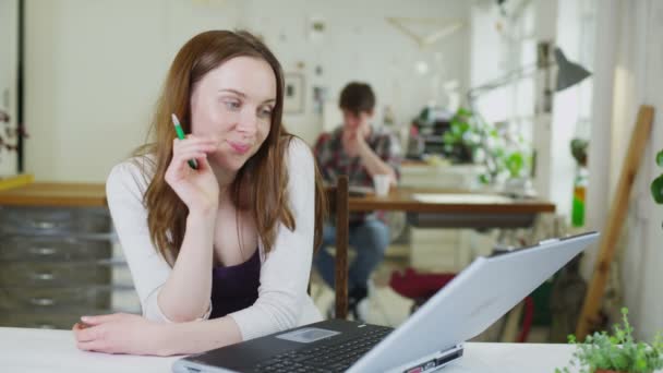 Young female student is distracted from her work in a shared study space — Stock Video