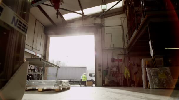 Trabajadores moviendo mercancías a través de la puerta abierta de un almacén — Vídeo de stock