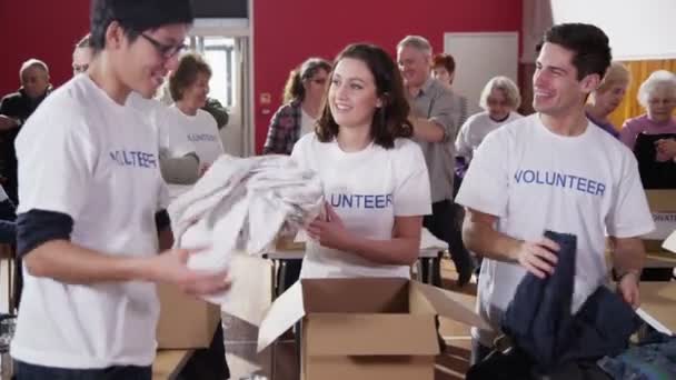 Liefdadigheid vrijwilligers sorteren door middel van gedoneerde goederen — Stockvideo