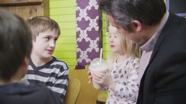 Aranyos kis lány élvezi a családjával egy kávézóban vele turmix — Stock videók