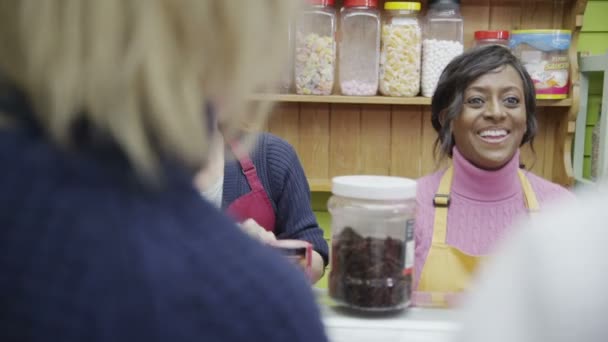 Personal amable de delicatessen que sirve a los clientes con una sonrisa en el mostrador de queso — Vídeo de stock