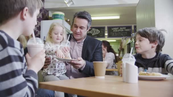 Gelukkig aanhankelijk familie genieten van snacks en drankjes in een café — Stockvideo