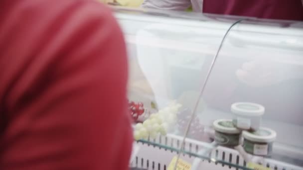 Vriendelijke delicatessen medewerkers bedienen van klanten met een glimlach aan de balie van kaas — Stockvideo