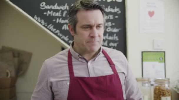 Shopkeeper derrière le comptoir prend un paiement par carte de crédit d'un client 