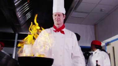 profesyonel şef yemek flambe stil bir ticari mutfak.