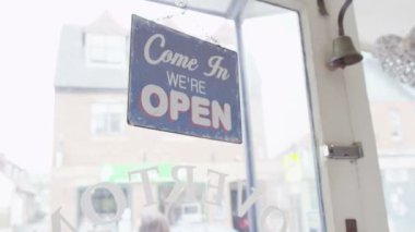Shopkeeper turns the 'Closed' sign to 'Open'