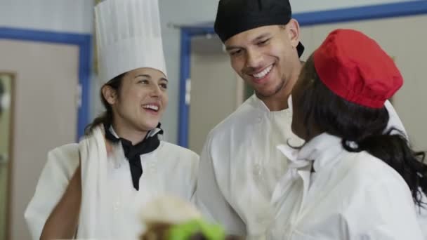 Equipo feliz de chefs en una cocina comercial, trabajando y compartiendo una broma juntos — Vídeo de stock