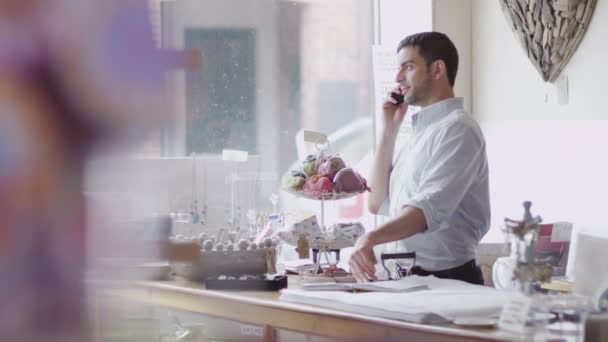 Winkeleigenaar maakt telefoongesprek op het werk — Stockvideo