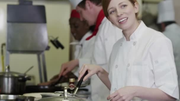 Equipo feliz de chefs en cocina comercial, preparando comida y charlando juntos — Vídeos de Stock