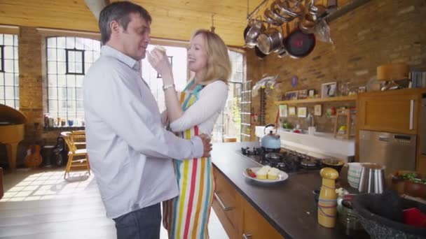 Зрелая пара становится романтичной на кухне — стоковое видео