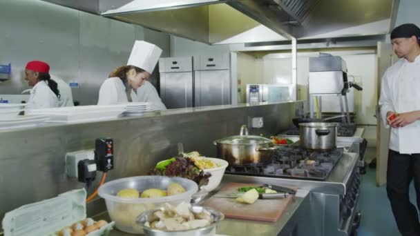 Zespół profesjonalnych kucharzy przygotowuje jedzenie w kuchni handlowych — Wideo stockowe