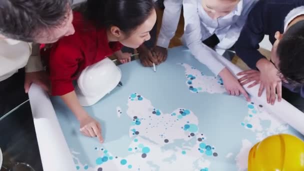 Cheerful mixed ethnicity team of architects or engineers looking at world map — Stock Video